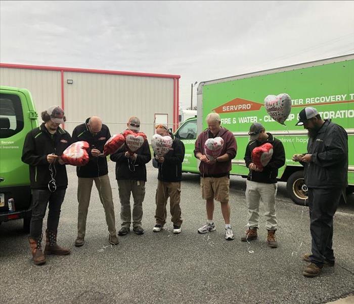 Valentine's balloons fly as SERVPRO technicians stand scratching of lottery tickets on Valentine's Day.