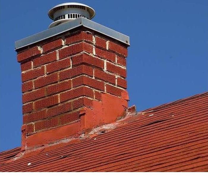 A brick chimney is shown on top of a roof 