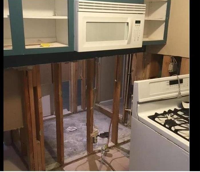 Drywall has been removed from a water damaged kitchen that is shown
