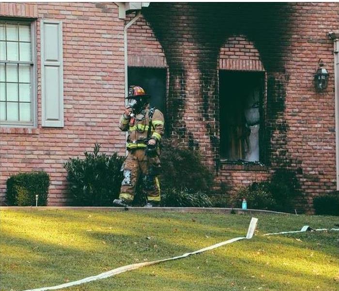 A First Responder is shown leaving a badly burned house 