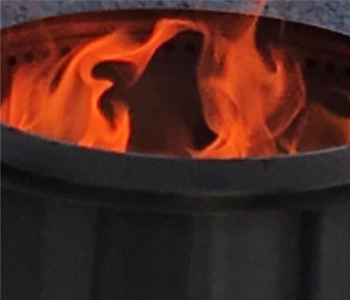 An outdoor fire pit is shown up close with flame