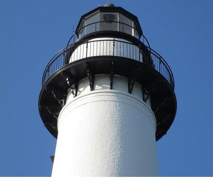 A white lighthouse is shown with black trim